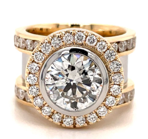 One yellow gold ring in a bezel set round cut diamond as a focal point of the ring and surround by smaller diamonds, directly facing the camera.