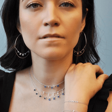 Woman is facing the camera and showcasing her gold jewlery pieces.