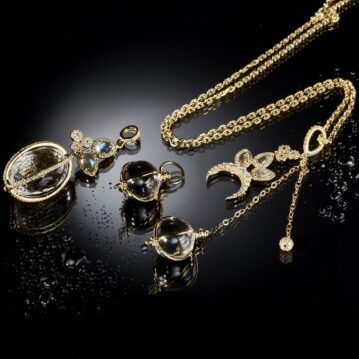 Gold diamond necklaces resting on a moist black surfaced.