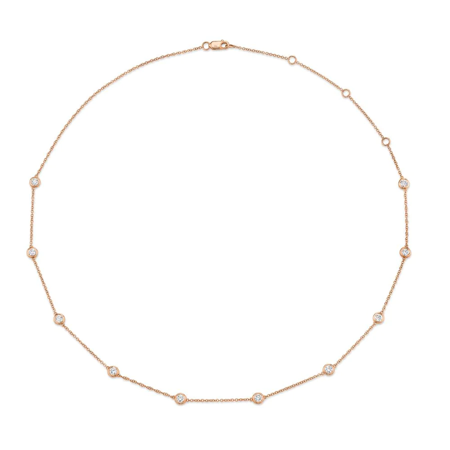One rose gold necklace. The necklace is a thin chain adorned with small circular diamond. The circular elements are evenly spaced along the chain and feature diamonds.