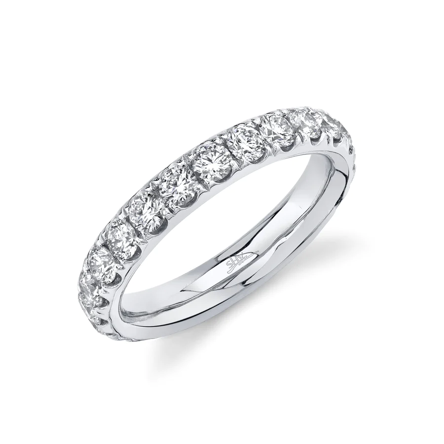 One white gold ring encrusted the band with a pave set round cut diamonds, it is placed slanted against a white background.