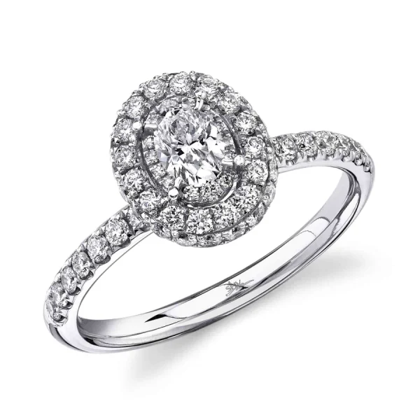 One white gold ring with a oval shaped diamond in the center surrounded by smaller diamond design, and the ring shoulder encrusted with pave set diamond, it is placed slanted on a white background.