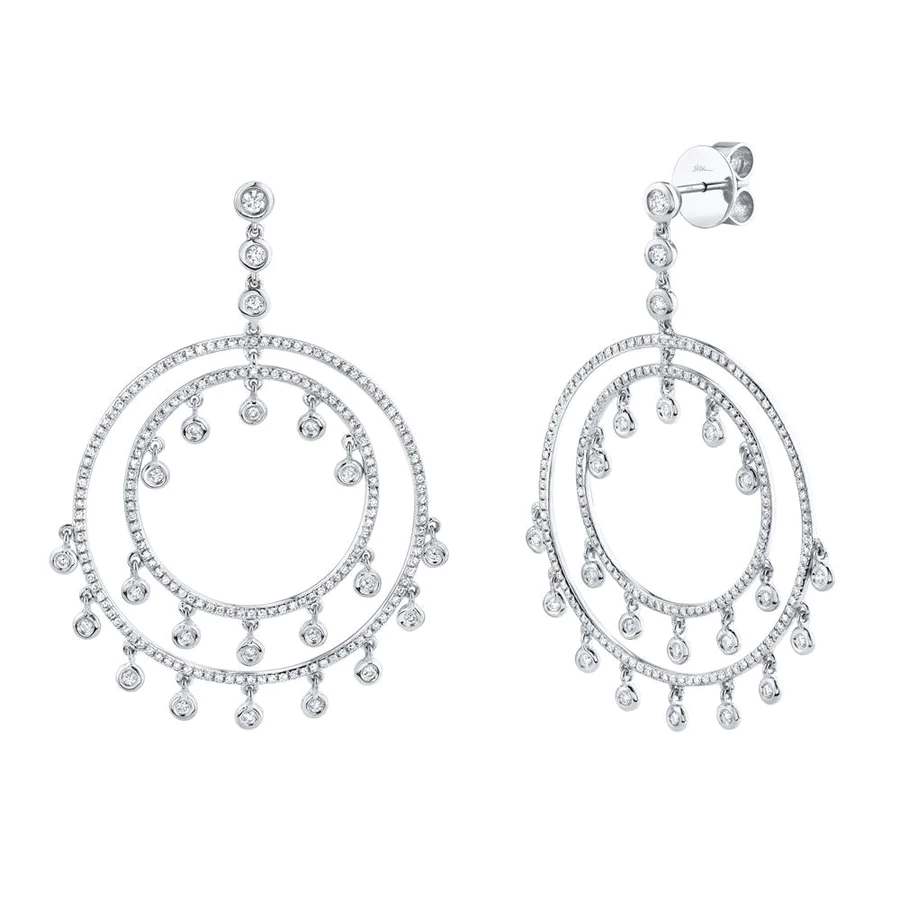 Two white gold earrings filled with diamonds and each earrings designed with two circles and has bezel set round diamonds hanging from the circles. The earring is on a white background.