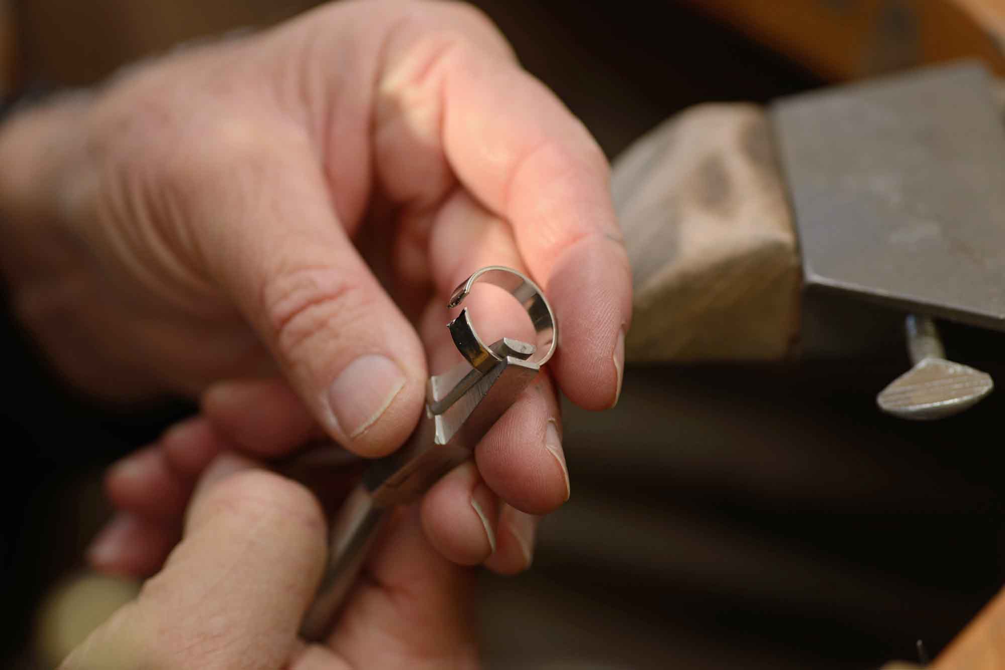 Jewelry technician working a band ring with pliers.