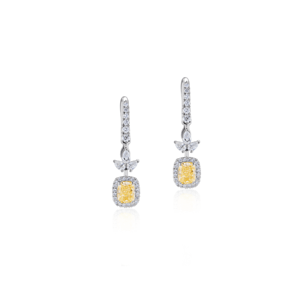 Two white gold earrings. The earrings are studded diamonds and feature a central yellow diamond surrounded by smaller diamonds.