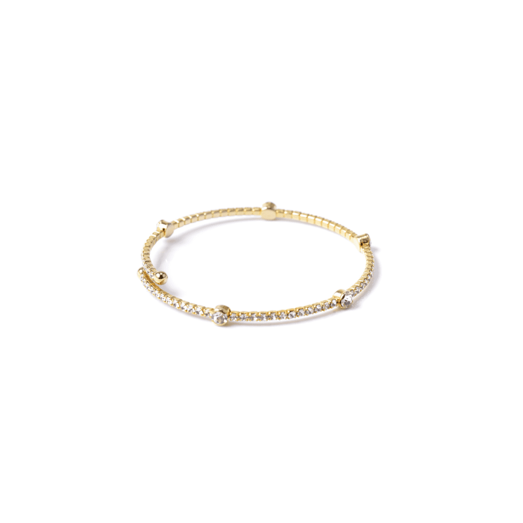 One yellow gold bracelet resting on a white table. The bracelet band feature a single cut diamonds and the circular elements are evenly spaced along the chain and feature diamonds.