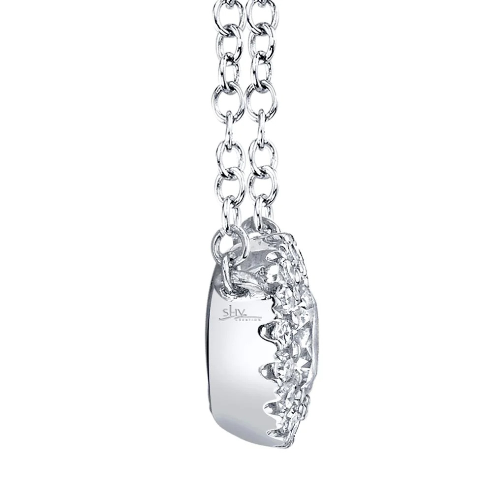 One white gold necklace facing on the left side from the camera. The necklace features a round pendant has center diamond surrounded by smaller side diamonds.