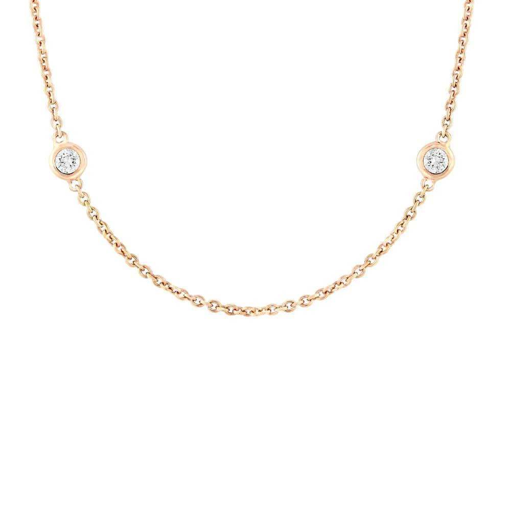 One rose gold necklace in a close-up view toward the camera. The necklace is a thin chain adorned with small circular elements. The circular elements are evenly spaced along the chain and feature diamonds.