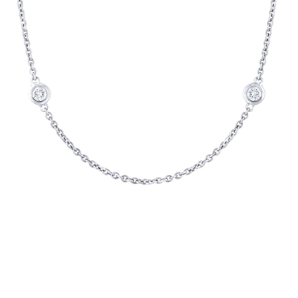 One white gold necklace in a close-up view toward the camera. The necklace is a thin chain adorned with small circular elements. The circular elements are evenly spaced along the chain and feature diamonds.