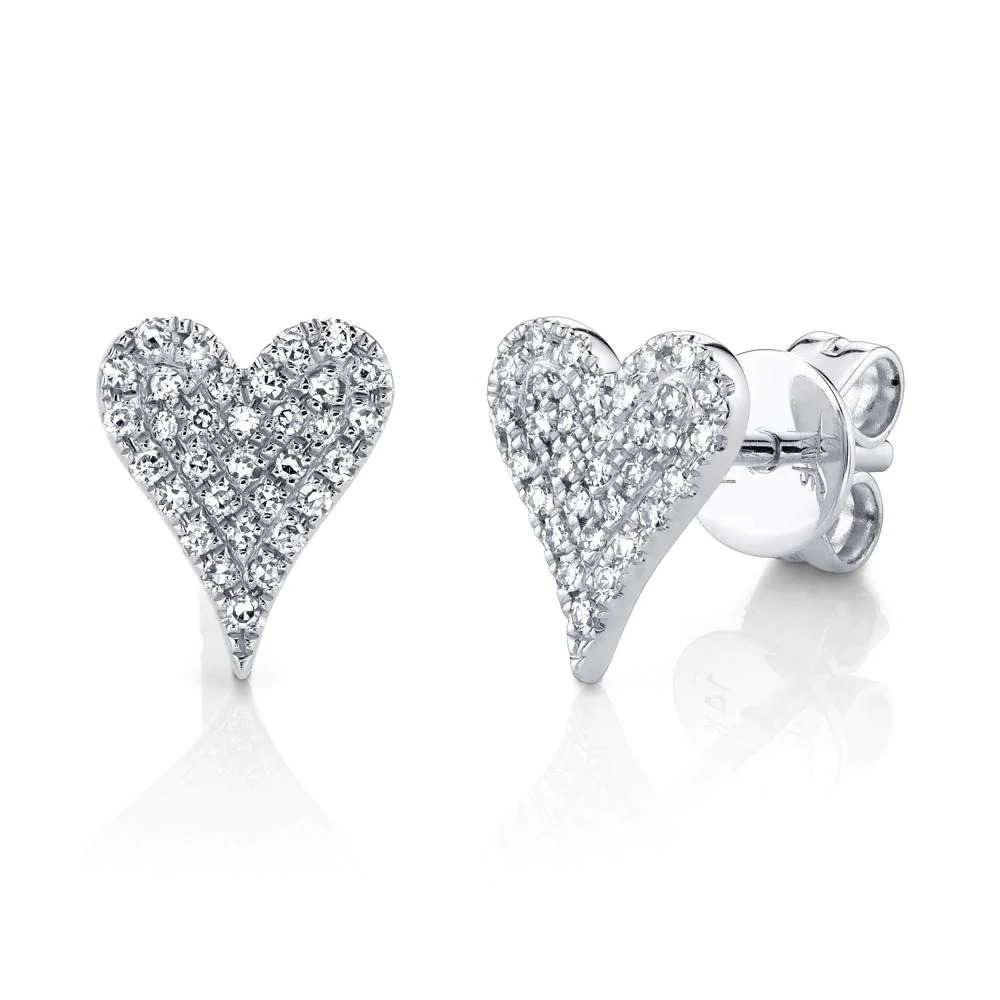 Two white gold stud earrings. The earring on the right is facing toward the camera, while the earring on the left is facing slightly to the right. The earrings feature a heart-shaped design with diamond stones.