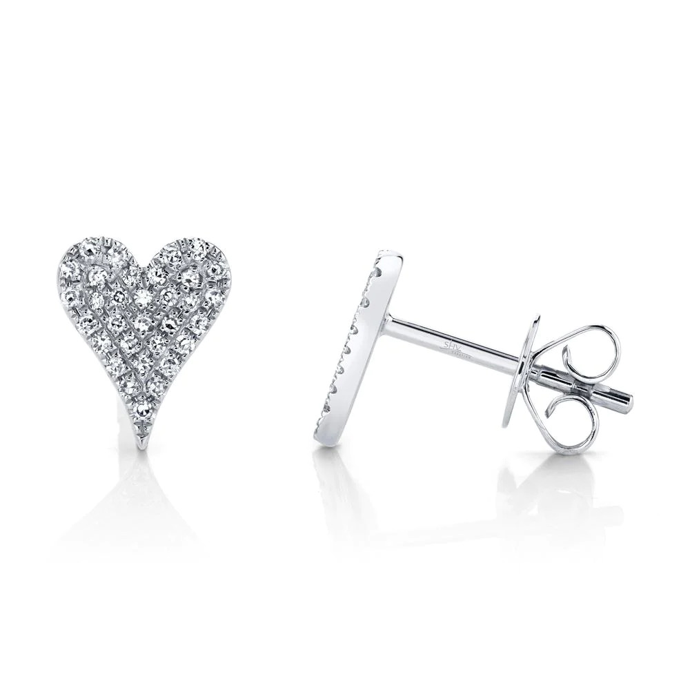 Two white gold stud earrings. The earring on the right is facing toward the camera, while the earring on the left is facing to the right. The earrings feature a heart-shaped design with diamond stones.