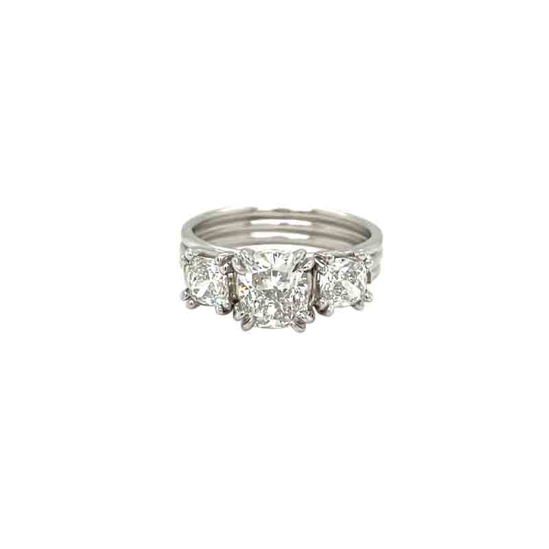 One white gold ring with a central focal point of three halo, cushion cut diamonds held by double prong, The ring sets on white background