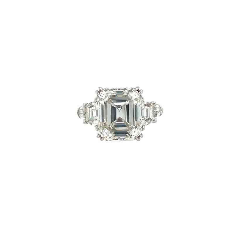 One white gold ring in a double prong set emerald cut diamond along with baguette from each side to the shank of the ring. The ring sets against a white background.