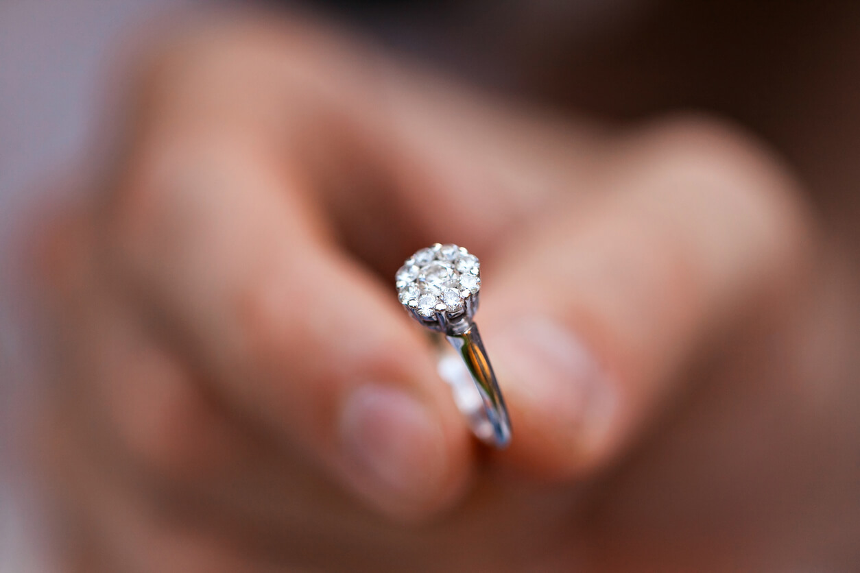 Man's hand holding a silver diamond ring